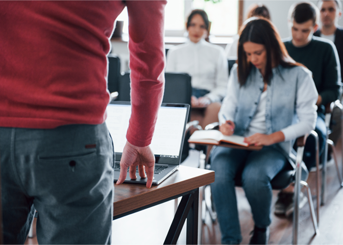 Personne qui donne une formation à un groupe de personnes qui écoute et prend des notes.