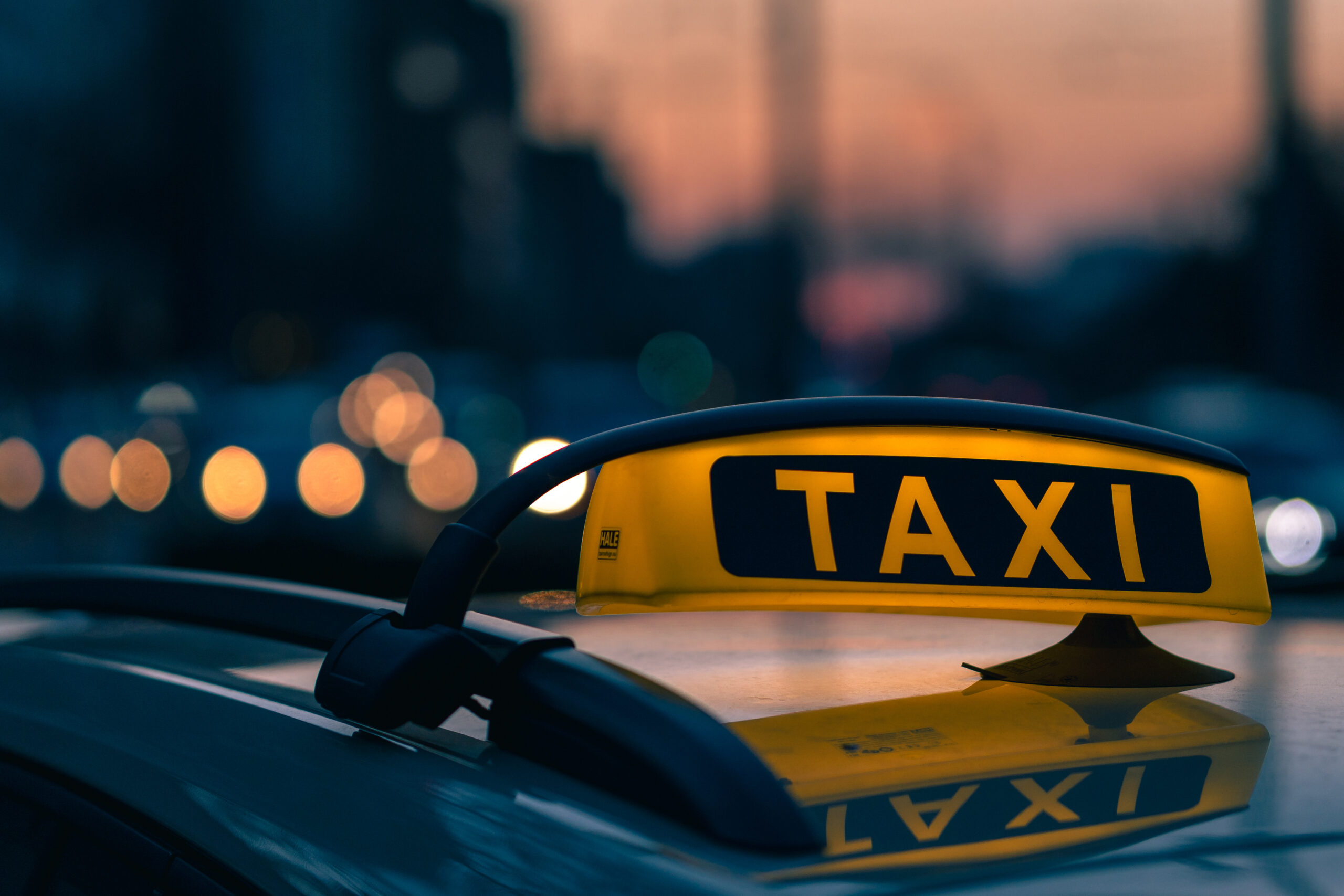 Lumineux d'un taxi avec en fond le trafic de voiture et le soleil qui se couche.